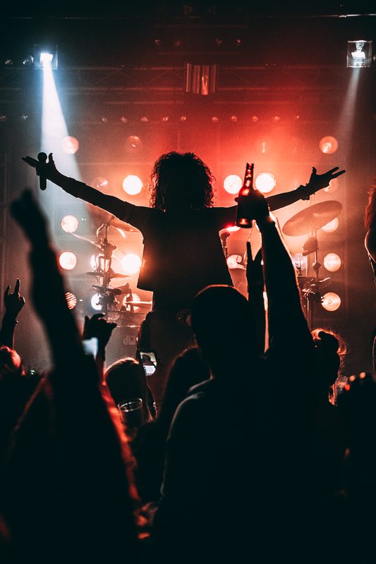 Crowd with hands up in front of a lit stage – The Jaded live